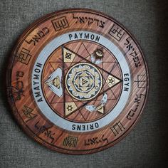 a circular wooden plaque with various symbols and words on it's sides, in different languages