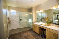 a bathroom with a walk in shower next to a sink and a large mirror on the wall