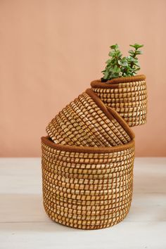 three woven baskets stacked on top of each other with plants growing out of one basket