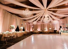 an elegant ballroom with chandeliers and white drapes draped over the dance floor