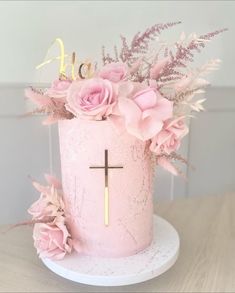 a pink cake decorated with flowers and a cross