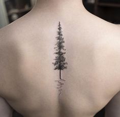 a woman's back with a tree tattoo on it