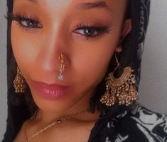 a close up of a person wearing jewelry and a hood over their head with her nose ring