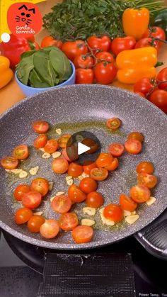 tomatoes being cooked in a frying pan on top of an electric stove with other vegetables