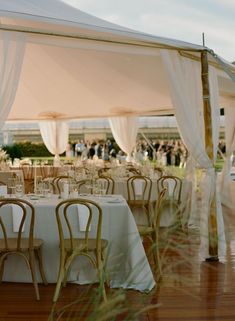 tables and chairs are set up for an outdoor wedding reception with white draping