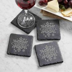 four personalized slate coasters with wine glass and cheese platter in the background