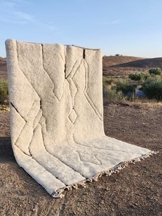 a large white blanket sitting on top of a dirt field in the middle of nowhere