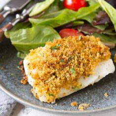 a close up of a plate of food with fish and salad on the side next to a fork