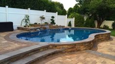 a pool with steps leading up to it and a white fence in the back ground