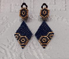 two pairs of blue and gold beaded earrings on a white cloth with black beads