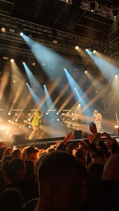 two people on stage with their hands up in the air and lights coming from behind them