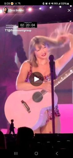 a woman holding a guitar in front of a screen with the words taylor swift on it