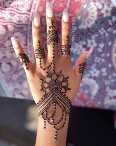 a woman's hand with henna tattoos on it