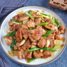 a white plate topped with chicken and green beans next to a piece of brown bread