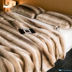 a bed that has some pillows on top of it and a cell phone in the middle