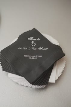 black and white napkins with wedding rings on them sitting on a table next to a clock