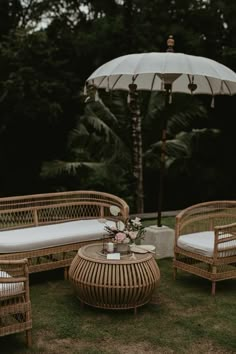 wicker patio furniture with an umbrella in the backgroung and white cushions