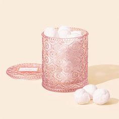 a pink glass cup filled with cotton balls