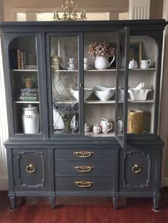 an old china cabinet with glass doors and gold trimmings on the bottom shelf