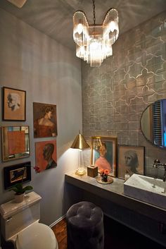 a bathroom with pictures on the wall and a chandelier hanging from the ceiling