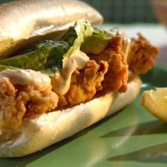 a close up of a sandwich on a plate with lemon wedges