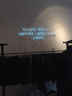 there is a neon sign that says music begins where language ends on the brick wall