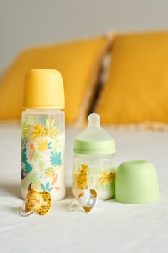 a baby bottle and pacifier sitting on a bed next to a pillow with yellow pillows