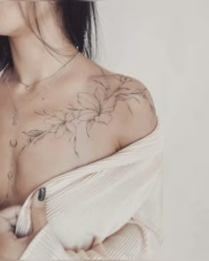 a woman with a flower tattoo on her chest and shoulder is looking at the camera