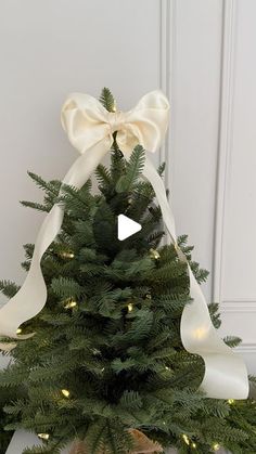 a small christmas tree with white ribbon and lights