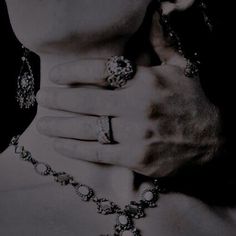 black and white photograph of a woman's hands with rings on her neck,