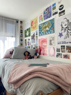 a bedroom with posters on the wall and a teddy bear sitting on top of the bed