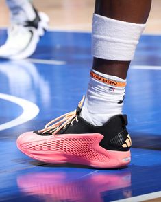 the feet of a basketball player in pink and black shoes on a blue court with white socks