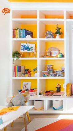 a room with yellow walls and white shelves filled with children's bookshelves