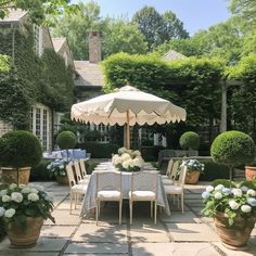 an outdoor dining area with potted plants and flowers on the table in front of it