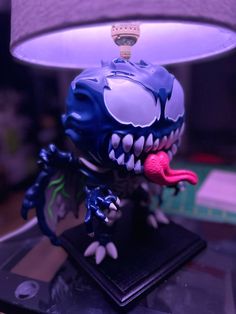 a lamp that has a blue and white monster head on top of it, sitting on a table