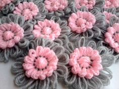 crocheted flowers are arranged on top of each other in grey and pink colors