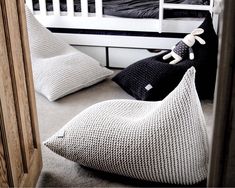 two stuffed animals sitting on pillows in front of a white bunk bed with black and white bedspread