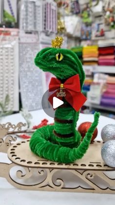 a green snake with a red bow sitting on top of a table