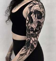 a woman's arm with a skull and flowers tattoo on her left arm, in black and white