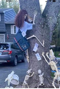 a woman standing next to a tree with skeletons on it