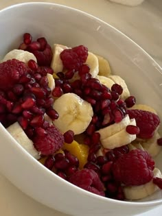 a white bowl filled with bananas and raspberries