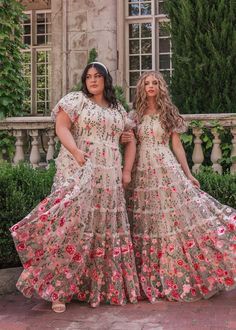 two women standing next to each other in dresses