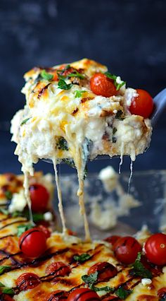 a slice of cheesy pizza being lifted with a fork from the casserole dish