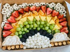 a box filled with fruit and pretzels in the shape of a rainbow on top of marshmallows