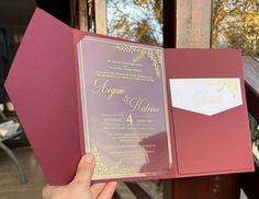 a person holding up a pink and gold wedding card