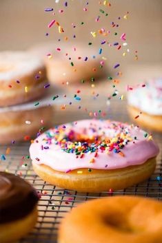 sprinkled doughnuts on a cooling rack, with one falling to the side