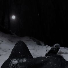 the person is laying down in the snow with their feet up on the ground at night