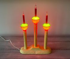 three lit candles sitting on top of a wooden table next to a corded light