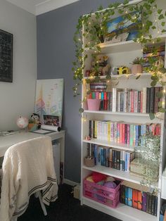 a book shelf filled with lots of books next to a white desk and computer monitor