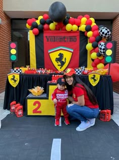 a woman and child posing in front of a balloon arch